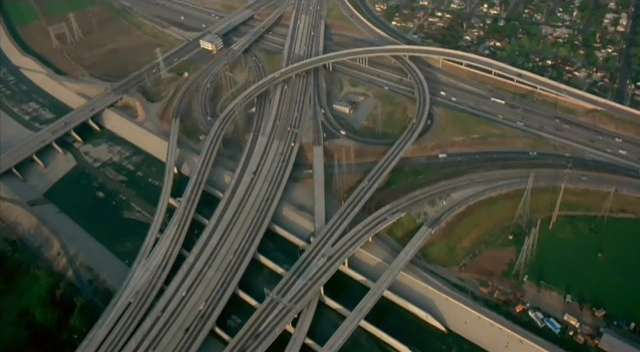 Freeway interchange, possibly in Los Angeles judging by the concrete flood-divert (LA River?) at the left and bottom.