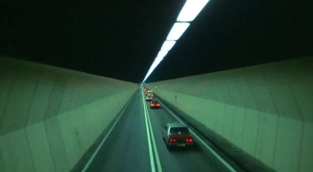 The image is easily recognizable as Hong Kong's distinctively-shaped Cross Harbour Tunnel, the first tunnel to connect Hong Kong Island to Kowloon.

The tunnel opened to the public in 1972, and so was around 15-16 years old at the time, unless this scene was stock footage.