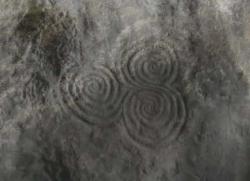 This Tri-spiral image is located in Newgrange passage tomb in County Meath, Ireland. The structure predates the pyramids and Stonehenge. Every year on the winter solstice the sun shines down the narrow passage and illuminates the chamber inside. This is where the trispiral is located.    