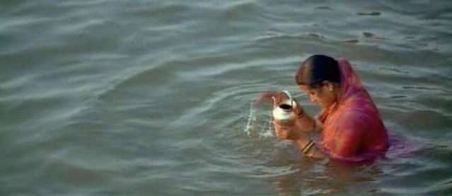 what the lady is doing is repenting. The cup full of water is her sins, and as she prays she dumps it out, as the water emptys out her sins go with it.